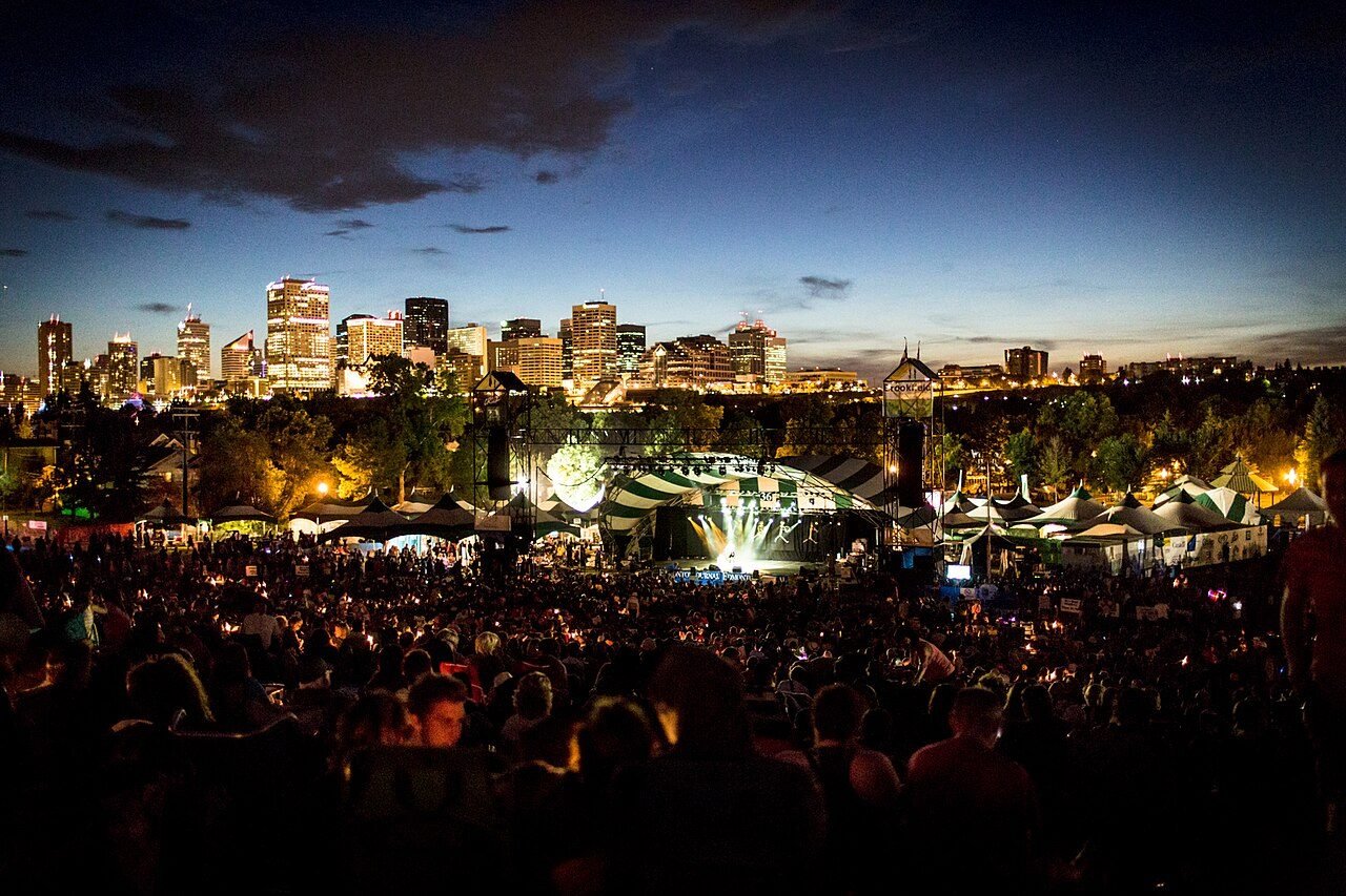 Night crowd on the hillside facing the lit main stage, with downtown Edmonton behind, 2015.